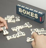 The black box is shown with its bone shaped dominoes put in a set for a dominoes game.