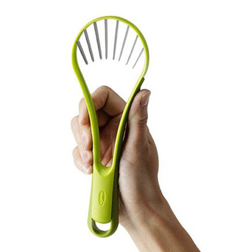 Green avocado slicer & peeler in hand.
