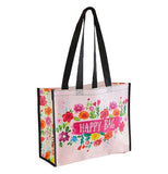 This light pink bag features the words, "Happy Bag" in white lettering against a hot pink sign. Surrounding the sign are a series of pink, purple, yellow, orange, and red flowers.