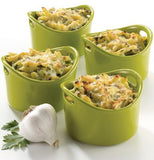 Four green ramekin dishes are shown with quiches in them and a garlic standing next to one of them.