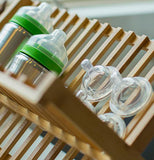 The clear silicone nipples are shown lying on a wooden dish rack.