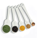 The Matryoshka doll-shaped measuring spoons are shown with different colored spices in them.