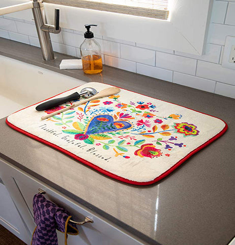 The "Thankful Grateful" drying mat is shown lying on top of a marble kitchen counter. An ice cream scoop and wooden spoon are shown both sitting on top of the mat.