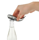 Silver whale bottle opener in use.