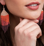 Two striped bead earrings worn in a models ears. The stripes are pastel pink, orange, darker pink, and red.