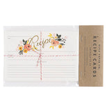 This set of white recipe cards feature a pink and yellow peony design at the middle top. They are shown in their packaging with the words, "Rifle Paper Co. Recipe Cards" in black lettering.