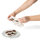 Some small ice cream sandwiches are shown being squeezed out of the baking dish and onto a plate.