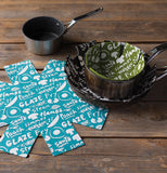 Snow flakes shaped pan protectors in blue with text on them on wood.