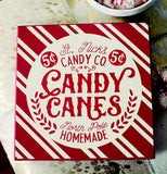 The red and white "Candy Canes" wooden box sign is shown lying on a table next to a bowl of mints.