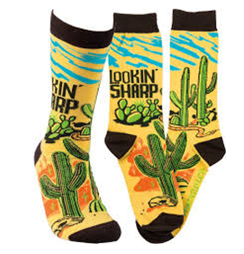 These yellow socks have black toes, heels, and tops. A green cactus print image shows an orange desert background and wavy blue streaks at the top. Above the green cactus are the words, "Lookin&
