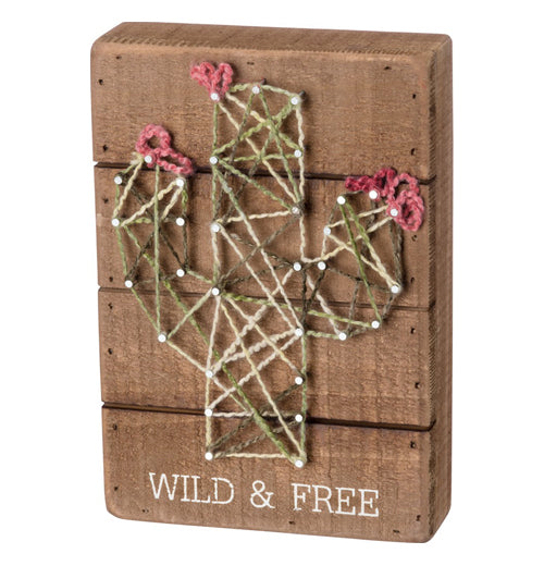 Green, pink, and white cactus string art with "Wild &amp; Free" in white on wood over a white background.