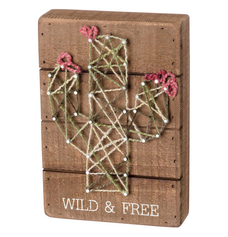 Green, pink, and white cactus string art with "Wild & Free" in white on wood over a white background.