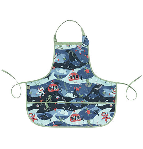 This blue kiddie apron has a design of sharks, whales, divers, and submarines covering it and green tying strings.