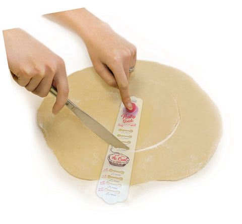 The pastry guide is shown helping a person cut a circle in some cookie dough.