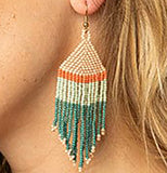 A striped bead earring worn in an ear. The stripes are pastel pink, dark orange, pastel green, and dark teal.