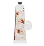 White tube of shea butter lotion with bee and floral design with some lotion smeared beside the tube on a white background.