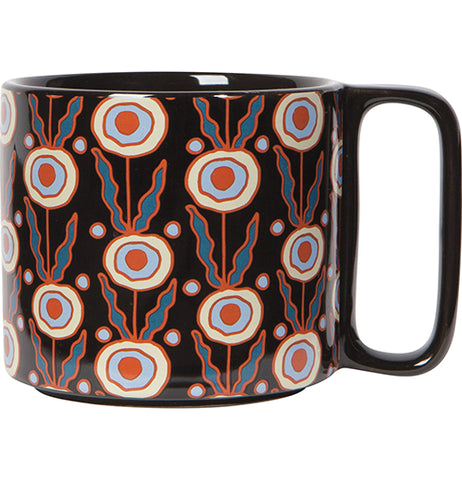A black mug with a red, darker blue, pastel yellow, and darker blue abstract design.