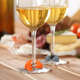 Orange and gray winer dog drink markers placed on the stems of filled wine glasses.
