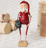 Sleepy time Santa wearing red pajamas and stocking cap holding a black teddy bear on a wooden block standing next to corks on a white table. 